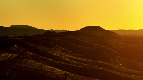 simpson desert arid outback landscape in yellow sunlight, 4k aerial telephoto drone flyover australia