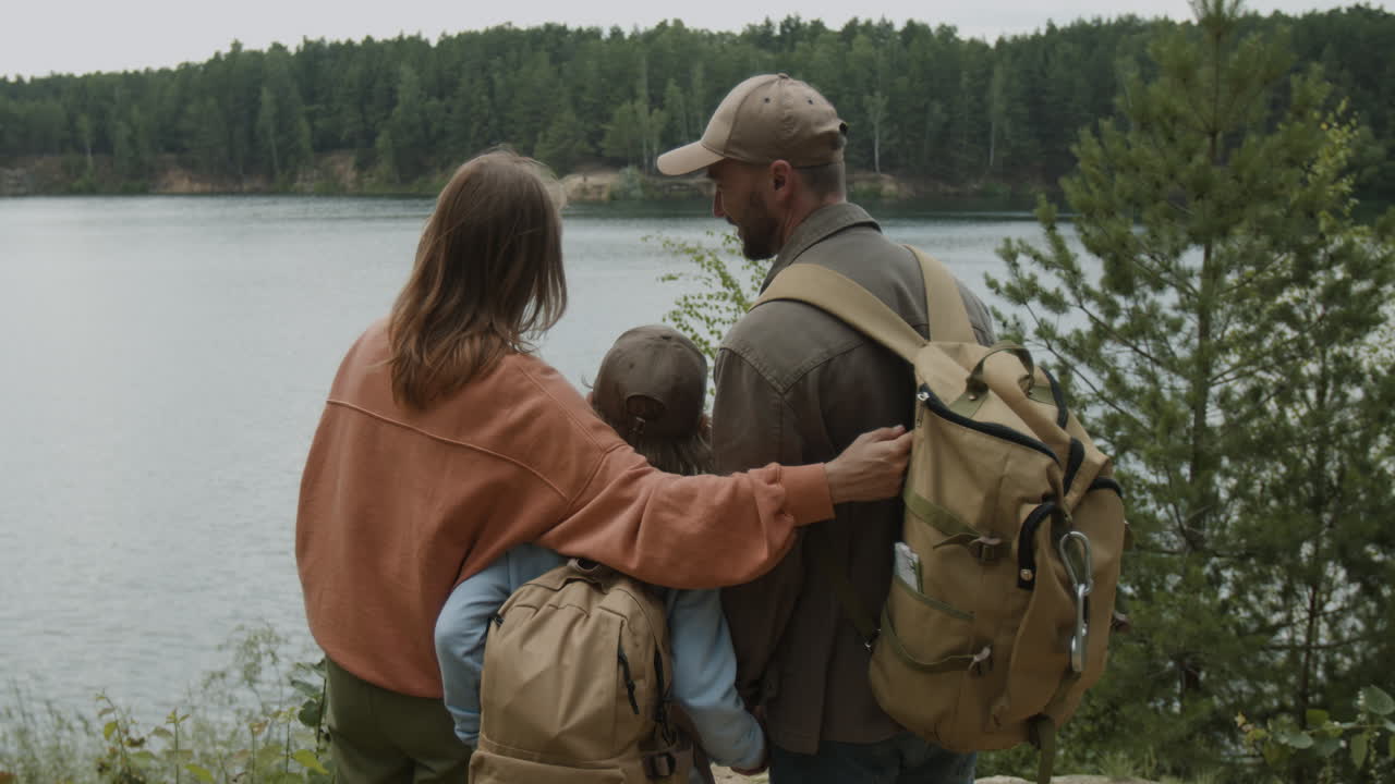 Perhe patikoi luonnossa järven rannalla