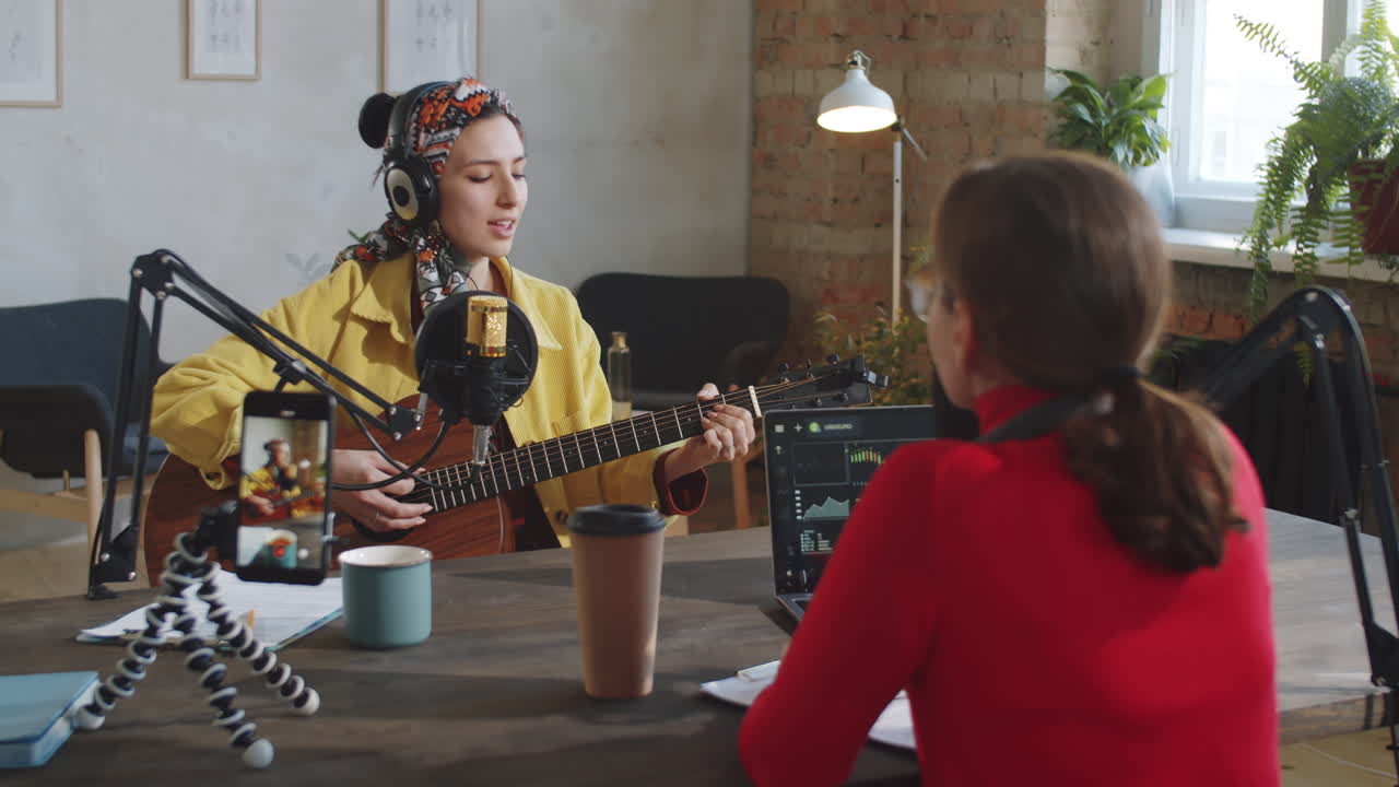 Donna che suona la chitarra e canta mentre registra un podcast.