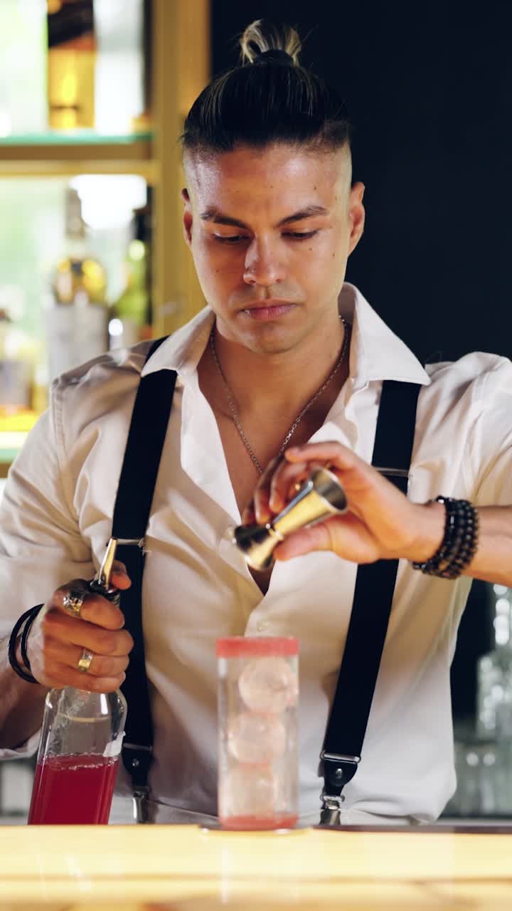 Barman professionista che versa del liquido rosso per cocktail in un misurino