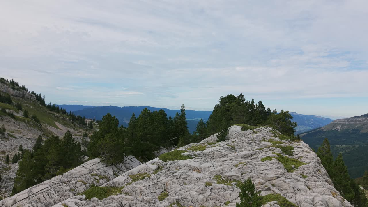 Luftfoto af Auvergne-Rhône-Alpes bjergkæden i Frankrig med grønne træer og en skyet himmel. Dette naturskønne landskabsfotografi fanger en rejsedestination fra oven