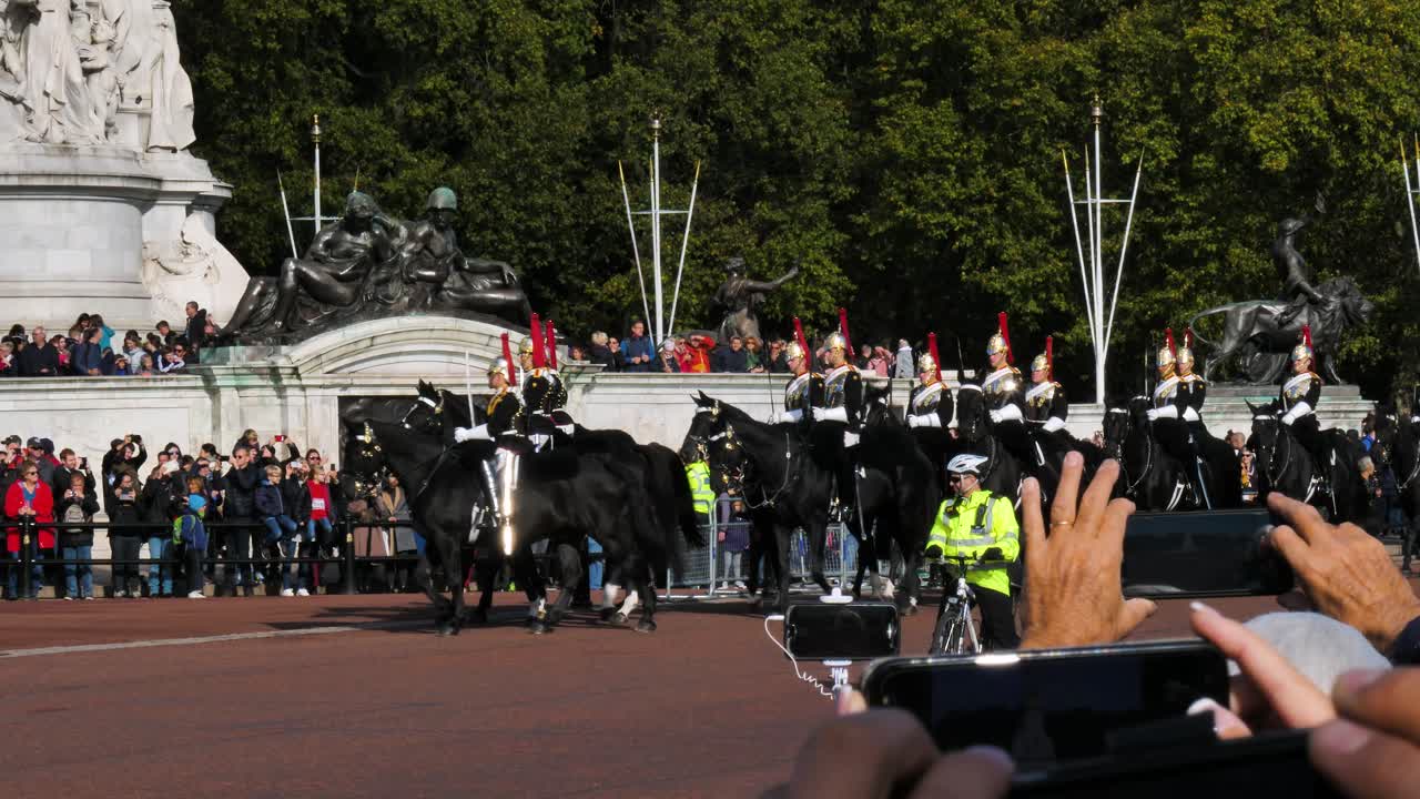 Queen's Horse Guards Parade in front of Buckingham Palace in London, UK. The life guards of the Queen pass by a crowd of tourists beneath the Victoria Memorial during a traditional royal ceremony.