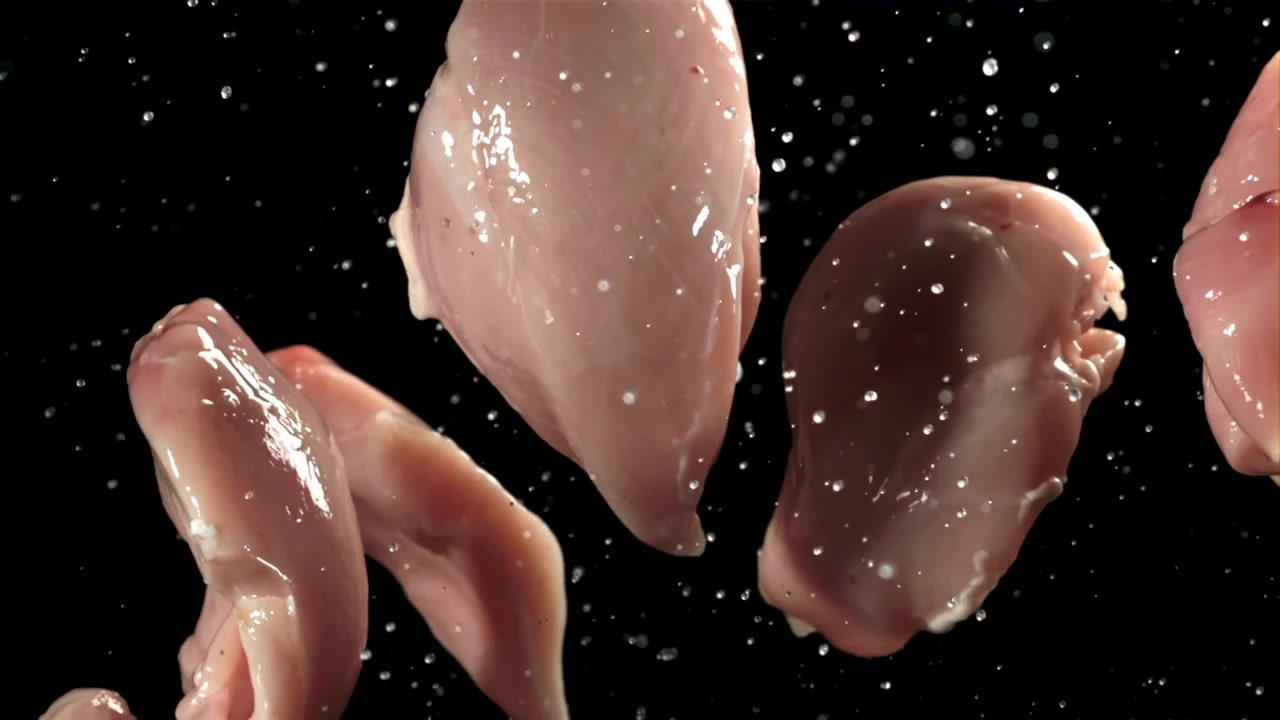 Fresh Raw Chicken Breast Falling with Water Droplets on Black Background
