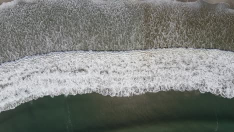 enormes olas rompiendo en una playa de arena