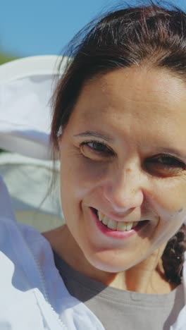 a woman adjusts her beekeeper's suit and smiles