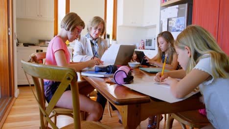 madre usando computadora portátil mientras los niños hacen su tarea 4k