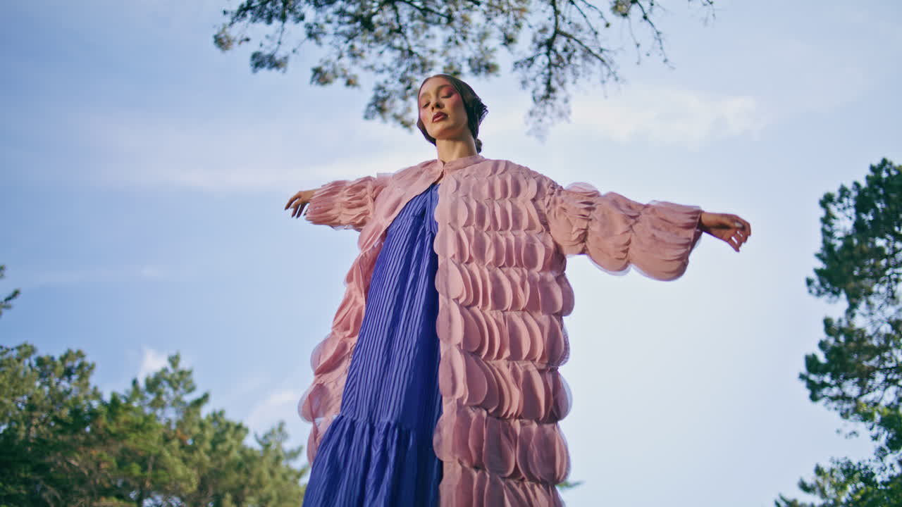 숲의 풍경에 서 있는 마법의 여인. 푸른 스카이라인에서 포즈를 취하는 웅장한 소녀.