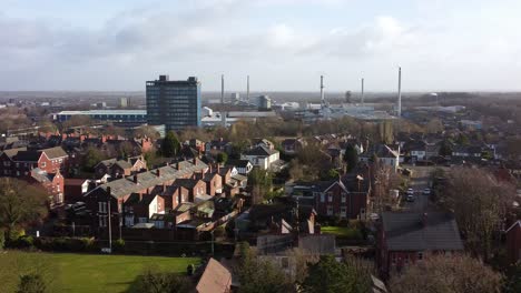 Panorámica-De-Vista-Aérea-A-Través-De-Los-árboles-Del-Parque-A-La-Propiedad-Industrial-Del-Paisaje-Urbano-Con-Rascacielos-Azul,-Merseyside,-Inglaterra