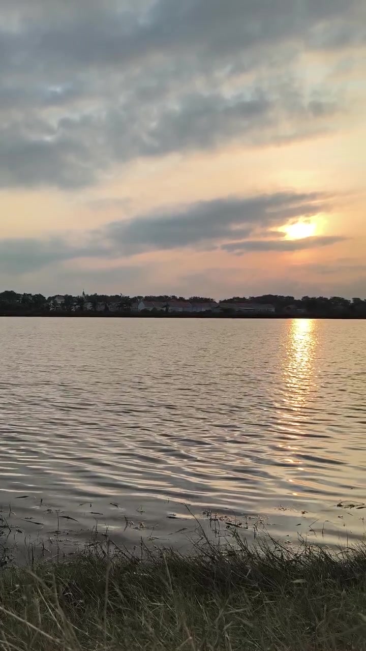 Tramonto dorato su lago calmo con riva distante