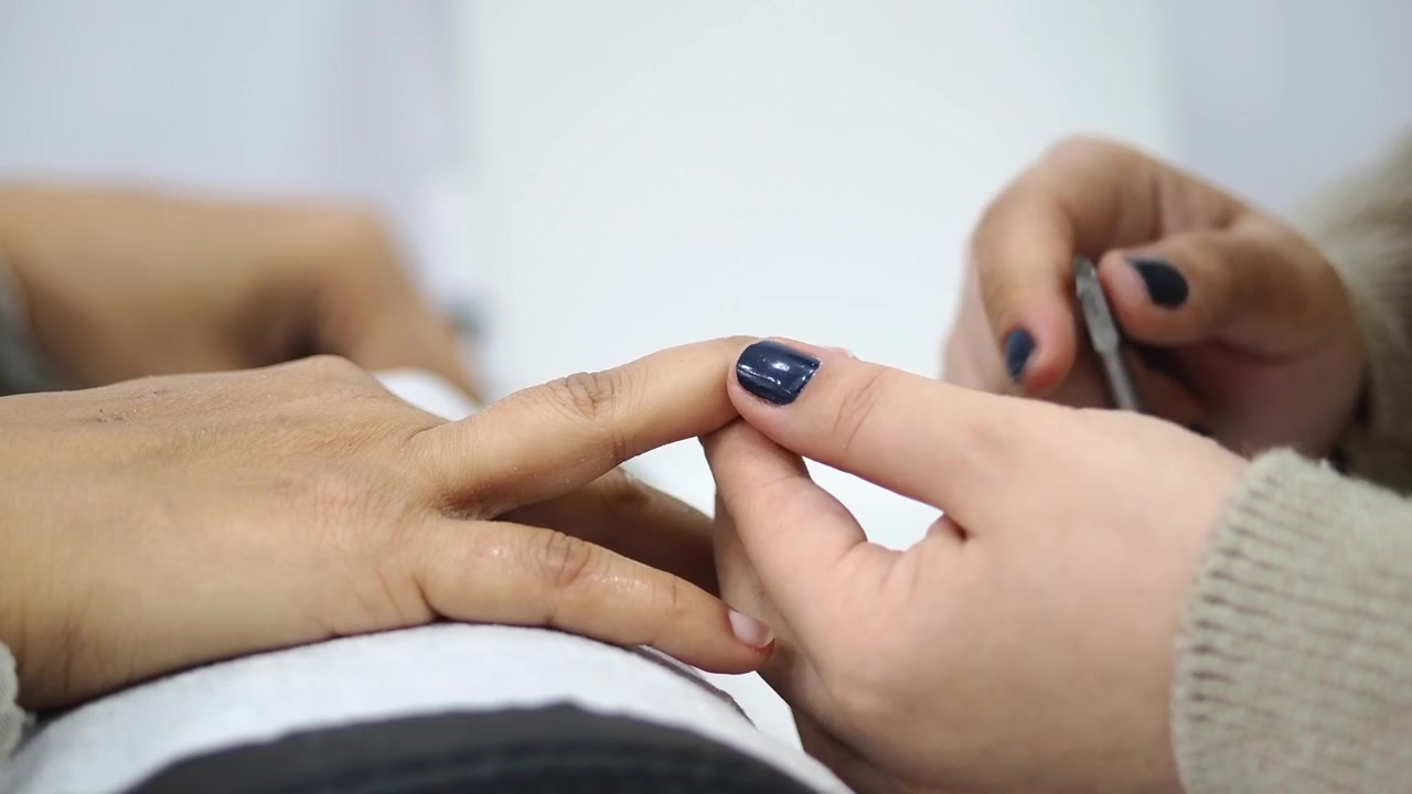 Manicurista che taglia le cuticole di una cliente in un salone di bellezza