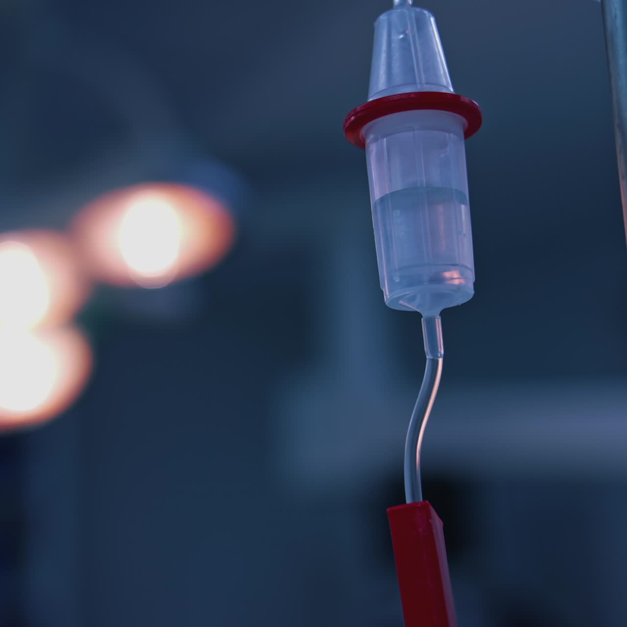 Medicina che gocciola durante l'intervento chirurgico. Flebo endovenosa in sala operatoria su sfondo sfocato di una lampada medica. Flebo durante un'operazione chirurgica in clinica. Primo piano.