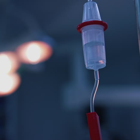 medicine dripping during surgery. intravenous dropper in surgery room on blurred background of medical lamp. dropper during surgical operation in clinic. close-up