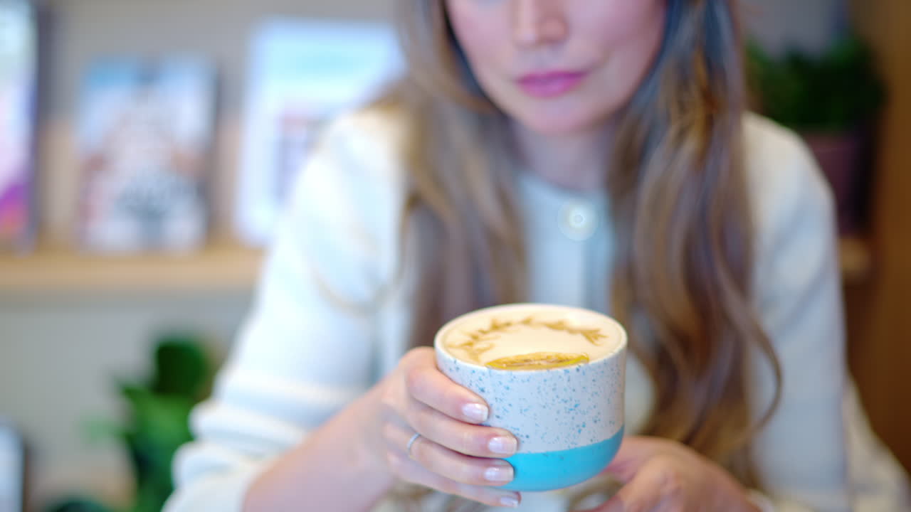 Woman drinking latte art coffee from ceramic cup in a cafe
