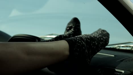 close up of woman's feet dancing on car dashboard