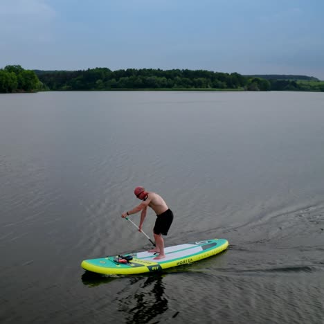 man standing on sup board. handsome young man on sup paddle standing board