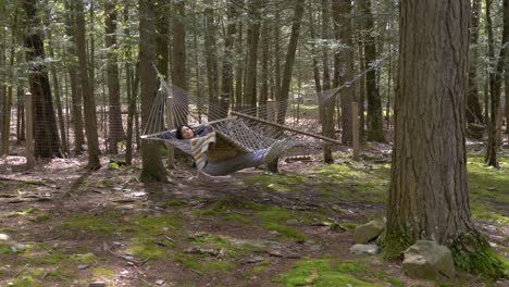 carefree young female swinging in woodland forest hammock relaxed and peaceful