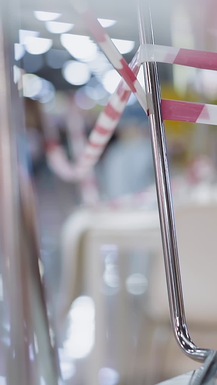 Chrome legs of chairs with colorful warning strip stand on table in closed cafe and blurry guy running along shopping mall closeup slow motion