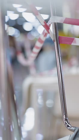 chrome legs of chairs with colorful warning strip stand on table in closed cafe and blurry guy running along shopping mall closeup slow motion