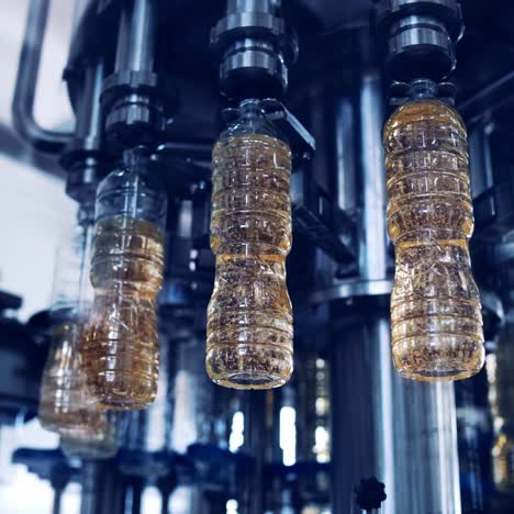 equipos robóticos en la fábrica de aceite comestible. equipos industriales modernos vertiendo aceite de girasol en las botellas que se mueven en una línea de producción de círculo.