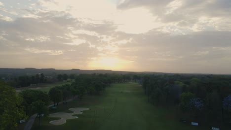 aerial drone shot offering a breathtaking top-down view of a golf course in delhi, highlighting its well-maintained layout and surrounding urban skyline.