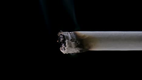 Zooming-in-Shot-of-the-Tip-of-a-Cigarette-Slowly-Consuming-itself,-Emitting-a-Trail-of-Smoke,-in-Front-of-a-Black-Background