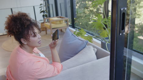 holding smartphone, woman sitting on couch in modern living room, copy space