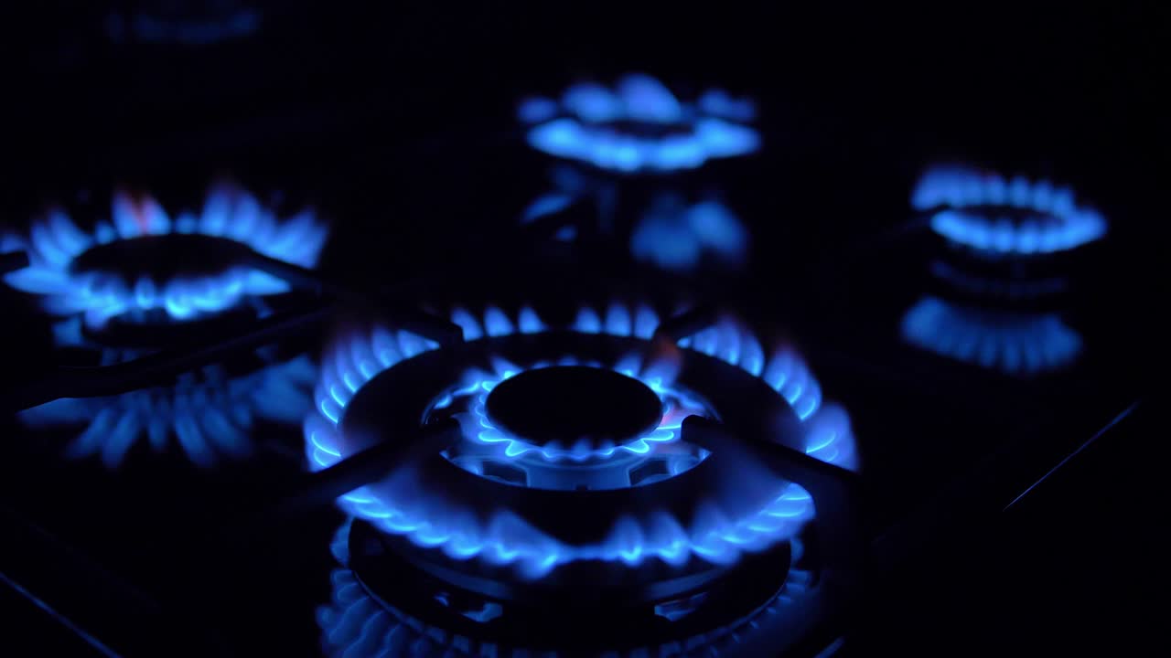 가스 스토브가 켜지고 꺼지고 파란 불꽃이 어 속에서 불타고 있습니다.