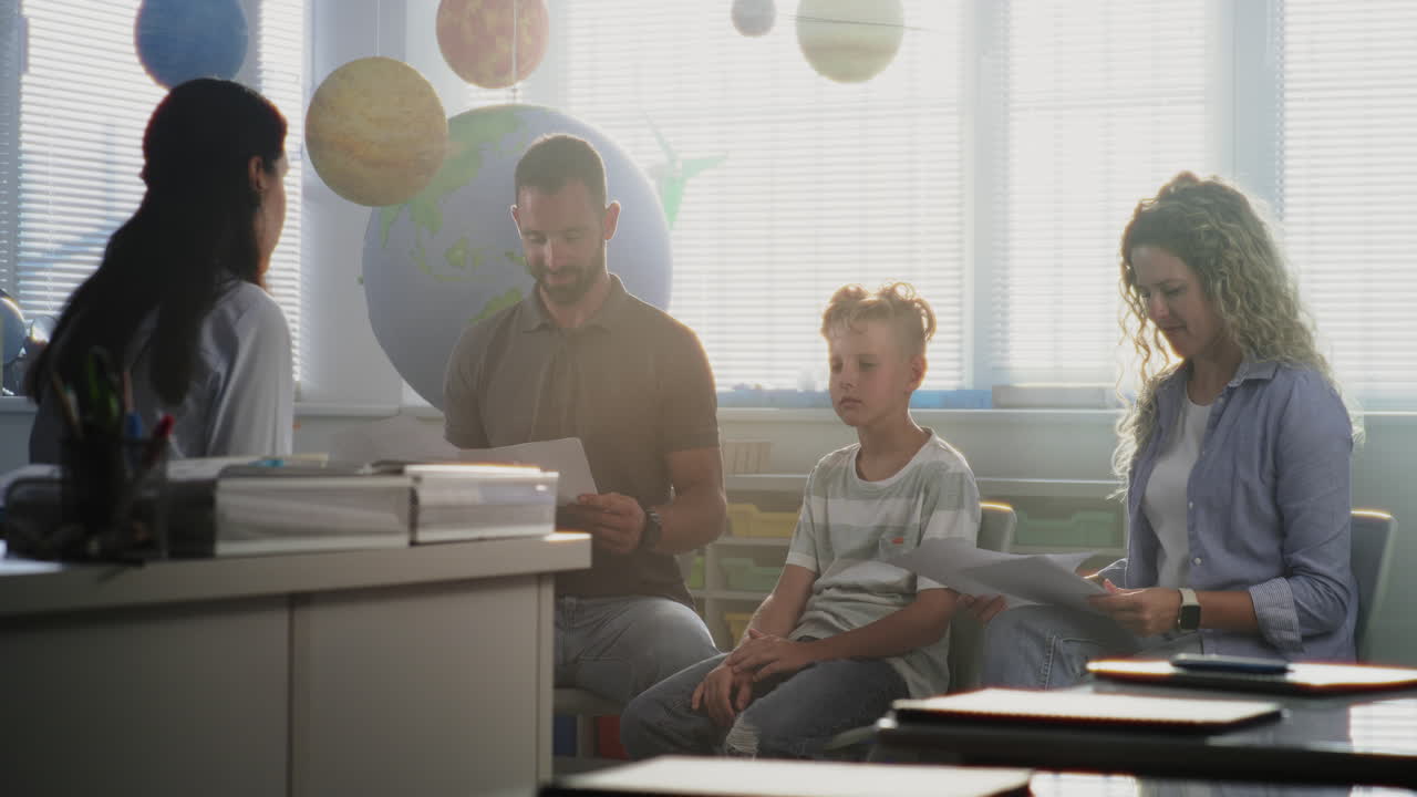 Mother and Father Looking at School Test Grades of Their Son During Parents Evening