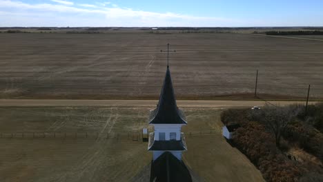 backwards flying drone revealing secluded old church in canadian countryside