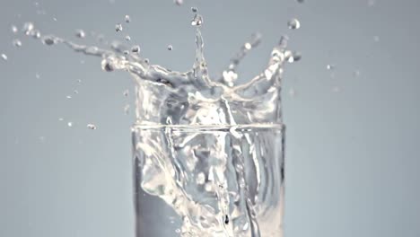 ice cubes falling into glass of water