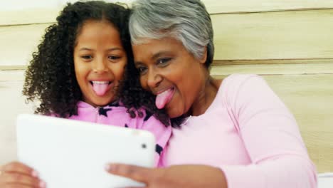 grandmother and granddaughter using digital tablet in bed room 4k