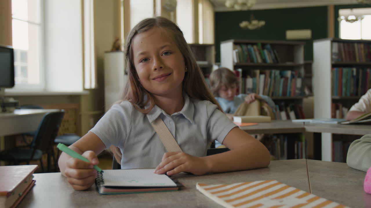 Young girl writing and smiling in a school library