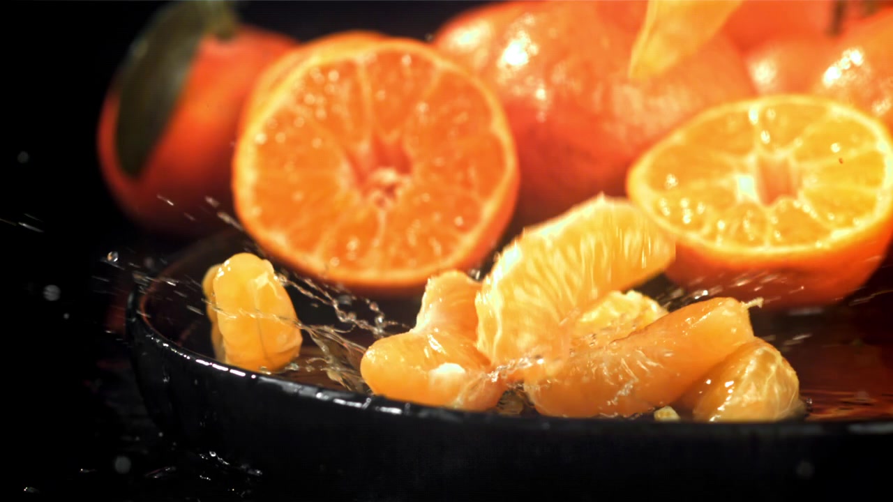 Spicchi di mandarino freschi che cadono e schizzano nell'acqua al rallentatore