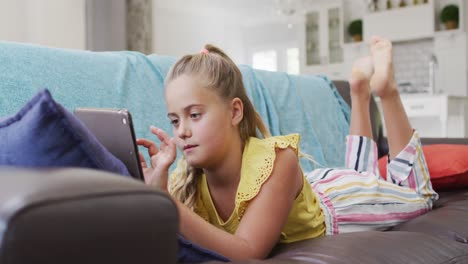 Glückliches-Kaukasisches-Mädchen-Zu-Hause,-Das-Mit-Einem-Tablet-Auf-Der-Couch-Liegt-Und-Lächelt