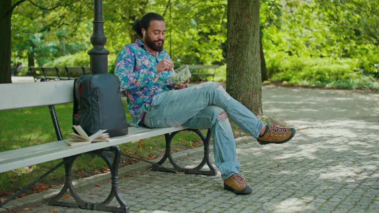 Un homme déjeune sur un banc de parc