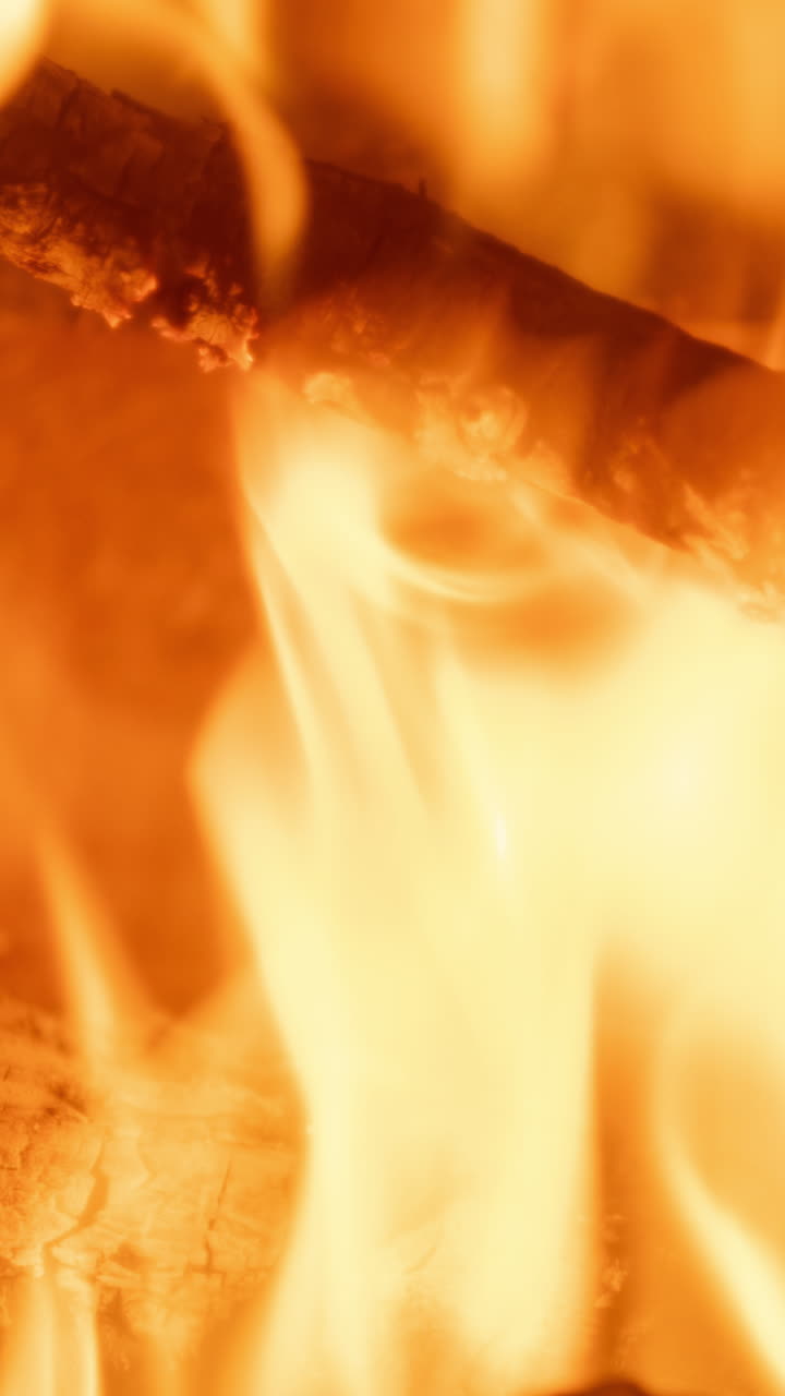Un primo piano di fiamme di un fuoco di legna che brucia in un camino, in verticale