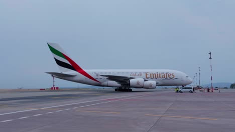 profile view of an emirates a380 taxiing to the gate at the airport