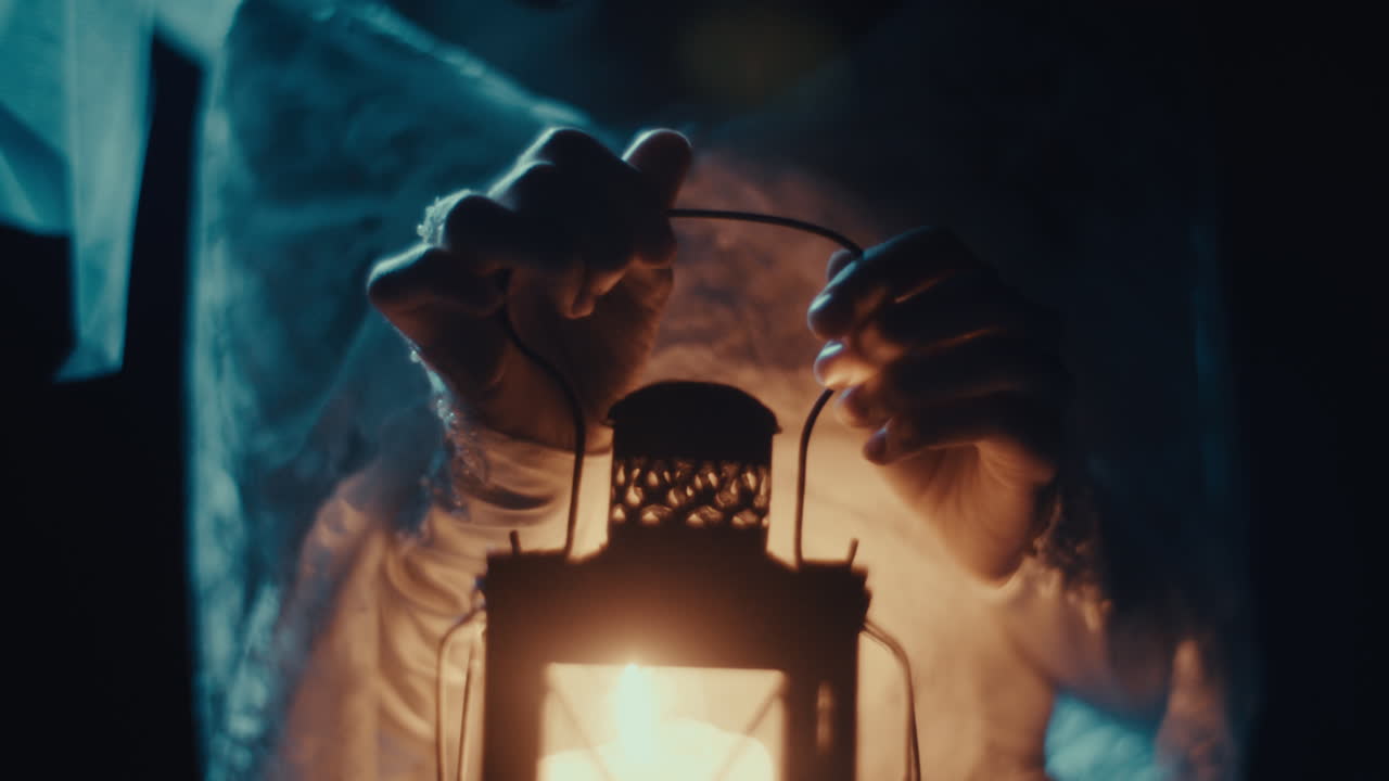 Hands Holding a Glowing Antique Lantern in Darkness