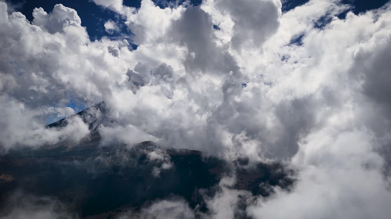 Static shot of the Popocatépetl volcano behind a cloud bank in Mexico