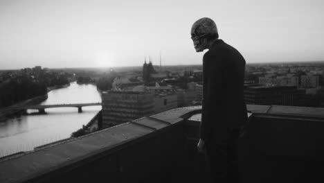 man in skull mask overlooking city at sunset from rooftop