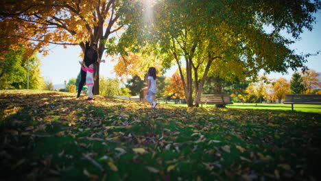 mother and daughters playing in autumn park