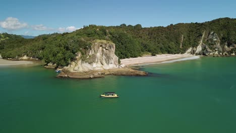 los barcos turísticos flotan entre los enormes acantilados de la bahía solitaria en whitianga mientras muestran el famoso espiráculo de la playa de los cocineros