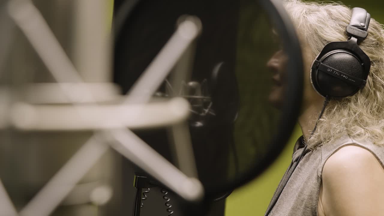 rubia mujer rubia de mediana edad cantando en un estudio de grabación, cámara lenta