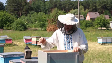 the beekeeper looks after bees, honeycombs, a lot of honey, in a protective beekeepers beast. concept: bee hive, pure natural product, useful product, yellow golden honey, swarm of bees, hard working.