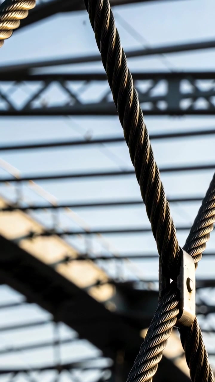 Video verticale: Telecamera in panoramica che segue cavi d'acciaio intrecciati su un ponte, evidenziando il bullone di serraggio.