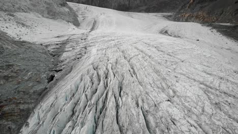 aerialf flyover over the ice and crevasses of hohlaub glacier near saas-fee in valais, switzerland with a pan down view towards the turquoise water of the glacial lake