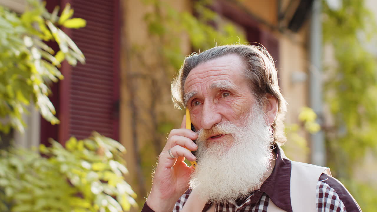 hombre feliz abuelo teniendo conversación remota hablar en el teléfono inteligente buenas noticias chismes en la calle de la ciudad
