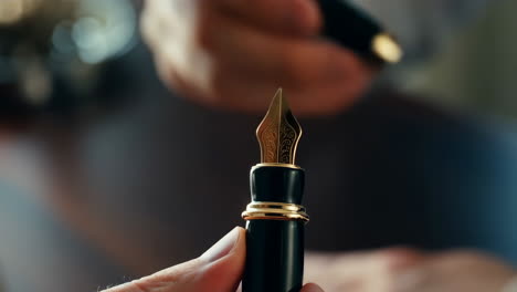 close-up of a luxurious golden fountain pen nib held by a hand