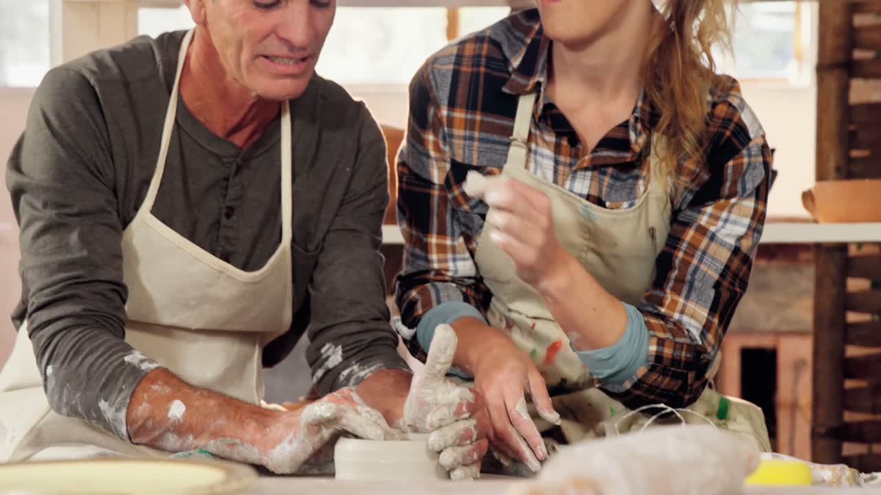 남자 와 여자 도자기 제작자 들 이  ⁇ 비 를 만드는 동안 재미 를 느끼고 있다