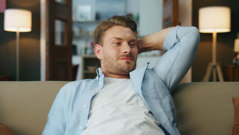 relaxed man chilling sofa evening home closeup. carefree gentleman sitting couch